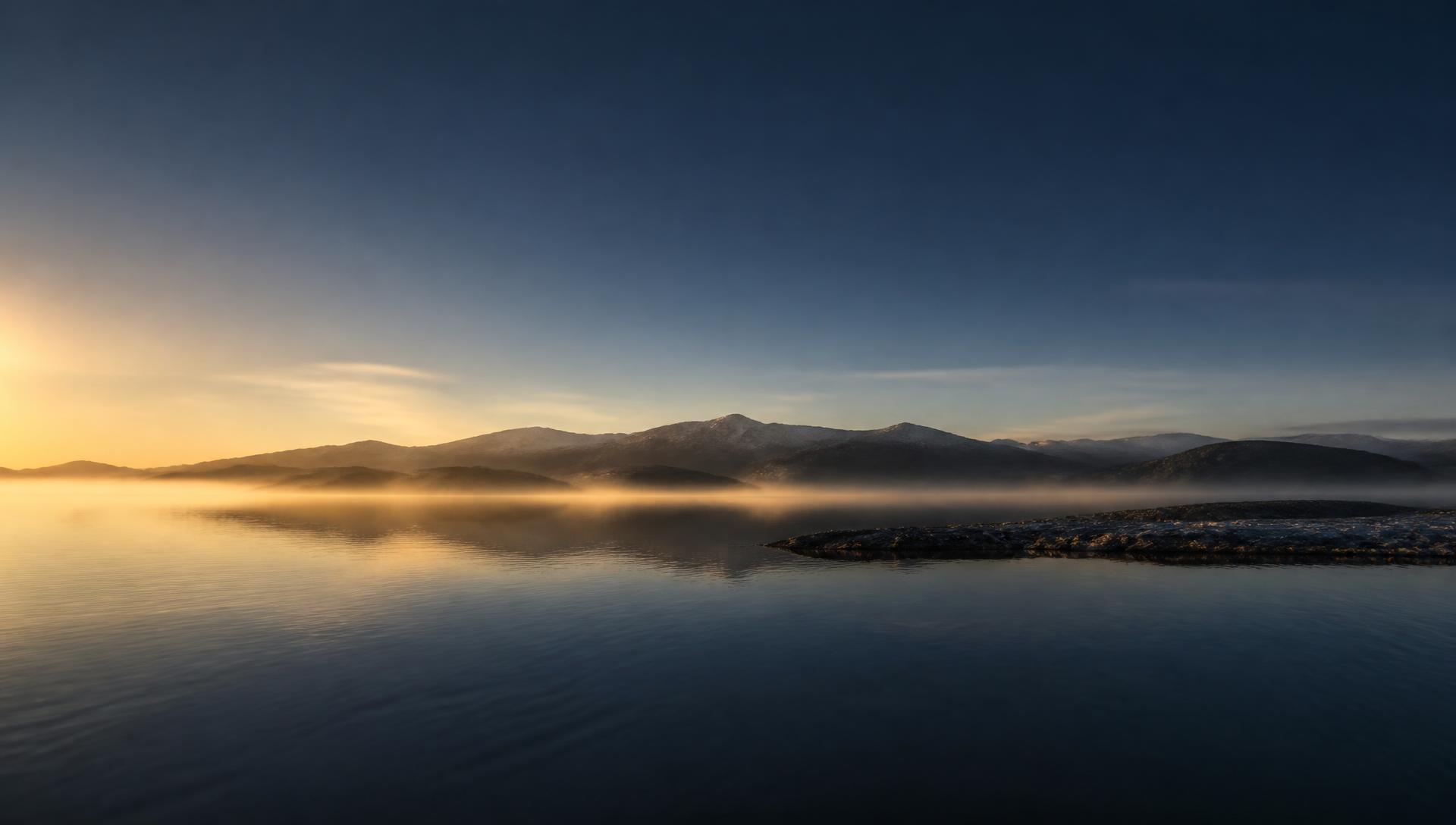 Calm water at first light beneath a distant ridge line